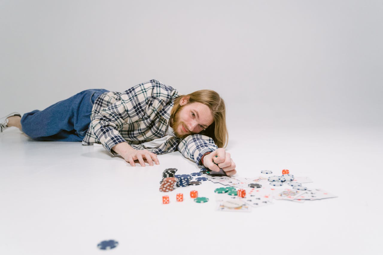 A man lying on the floor surrounded by cards and dice, enjoying leisure time.